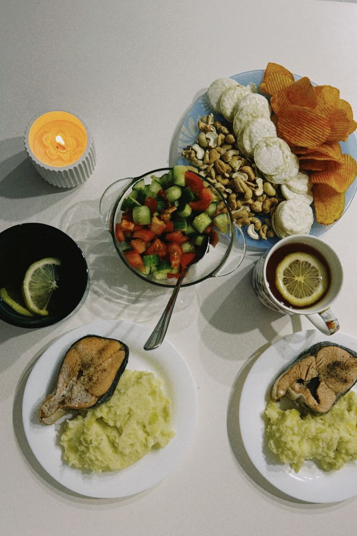 services-01 A delicious spread featuring fish, fresh salad, nuts, and tea, perfect for cozy evenings.