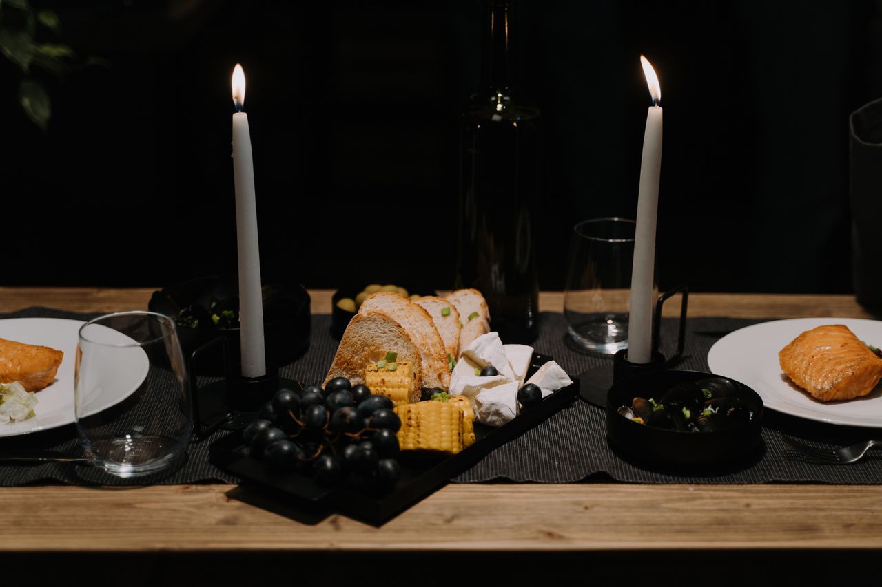 A romantic candlelit dinner setup featuring salmon, cheese, bread, and grapes for an intimate meal.